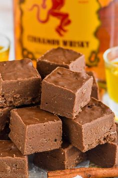 a pile of brownies sitting on top of a wooden cutting board next to a bottle