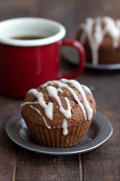 a close up of a muffin on a plate with a cup of coffee in the background