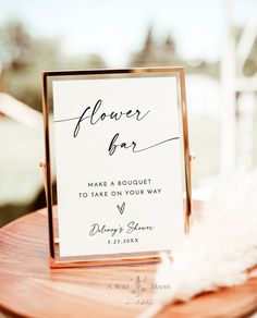 an open bar sign sitting on top of a wooden table next to a white feather