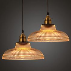 two pendant lights hanging from a ceiling in a room with dark walls and flooring