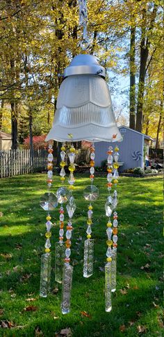 a lamp hanging from the side of a tree in a yard with grass and trees behind it