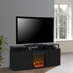 a flat screen tv sitting on top of a black entertainment center next to a fire place