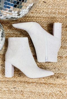 a pair of white boots sitting on top of a floor next to a disco ball