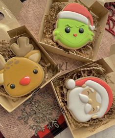 three decorated christmas cookies in boxes on a table