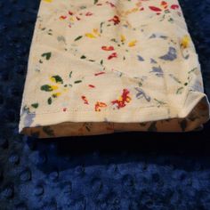 a cloth bag sitting on top of a blue carpet next to a white object with multicolored flowers