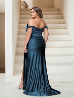 a woman standing in front of stairs wearing a blue dress with off the shoulder sleeves