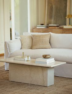 a living room with a couch, coffee table and books on top of the tables