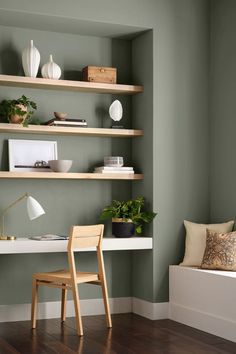 a room with green walls and wooden flooring, shelves on the wall are filled with plants