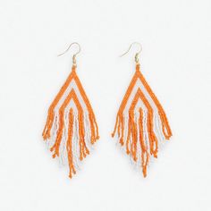 Cheer on your team in style with the Haley Game Day Stacked Triangle Beaded Fringe Earrings. These shoulder-dusting earrings feature layered triangle shapes strung with bright orange and crisp white seed beads in a bold colorblocked design. Tiers of beaded fringe dangle below, swaying gracefully with every movement. 4" L, 1.25" WHandmade by skilled artisans in India Hypoallergenic nickel + lead-free brass hardware These accessories are made by human hands. A slight variation in size and color is Orange Fringe Tassel Earrings For Summer, White Fringe Beaded Earrings For Summer, White Beaded Fringe Earrings For Summer, Handmade White Triangle Beaded Earrings, Orange Tassel Jewelry For Summer, Orange Beaded Fringe Jewelry, White Beaded Fringe Jewelry For Summer, Summer White Jewelry With Beaded Fringe, Summer White Beaded Fringe Jewelry