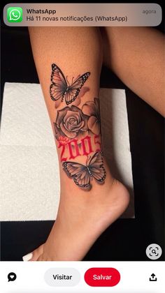 a woman's leg with butterflies and roses tattooed on the bottom of her legs