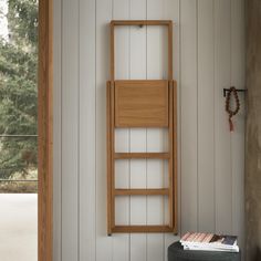 a wooden shelf on the wall next to a book case and magazine rack in a room with white paneling