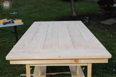 a wooden table sitting on top of a lush green field