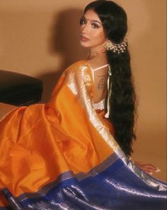 a woman sitting on top of a chair wearing an orange and blue sari dress