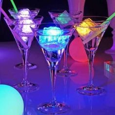 four martini glasses with ice cubes in them