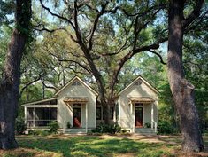 a small white house in the middle of some trees