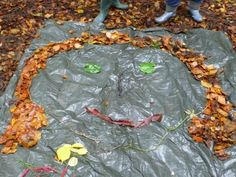 two children are playing with leaves on the ground in front of a circle made out of plastic