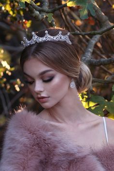 a woman wearing a tiara in front of a tree