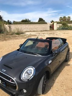 a small black car parked in the dirt