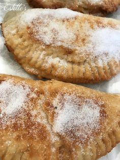 three pastries covered in powdered sugar on top of paper