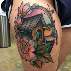 a woman's thigh with a bird house and flowers on it