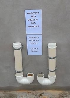 two white pipes are attached to the side of a building with a sign on it