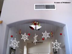 the bells are decorated with snowflakes and christmas decorations hanging from the ceiling in this hallway