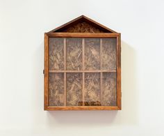 an old wooden shelf with glass doors on the top and bottom, in front of a white wall