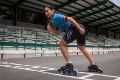 a woman riding roller blades on top of an empty parking lot next to bleachers