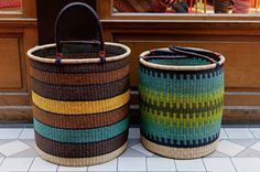 two woven baskets sitting next to each other on the floor in front of a store