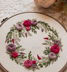 a close up of a embroidery on a table with flowers in the center and leaves around it