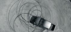 an aerial view of a car driving through a circular design on the ground in black and white