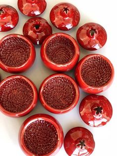 a group of red vases sitting on top of a white table