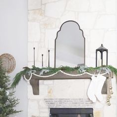 a fireplace decorated for christmas with stockings hanging from the mantel and candles on top