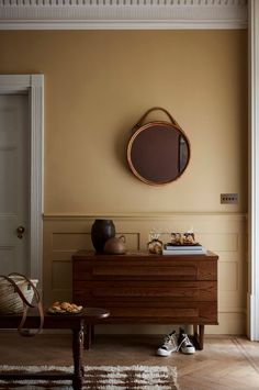 a living room with a dresser and mirror on the wall