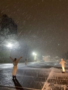 a person standing in the rain with their arms up and hands raised above their head