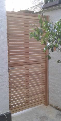 a wooden gate is shown in front of a white building with a tree growing out of it