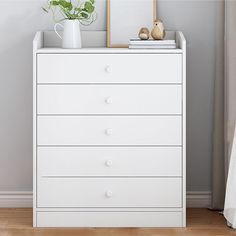 a white dresser sitting next to a window with a plant on it's top