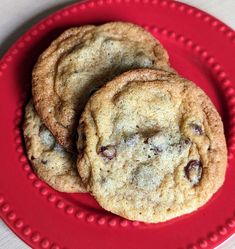 two chocolate chip cookies on a red plate