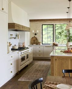 a kitchen with white cabinets and an island in front of a window that is open to the outside