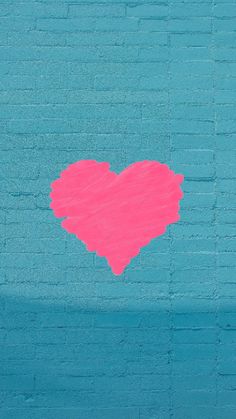 a pink heart painted on a blue brick wall