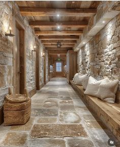 a long hallway with stone walls and flooring is lined with wooden benches, wicker baskets on either side of the bench