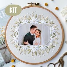 an embroidery kit with a wedding photo and flowers on it, surrounded by other sewing supplies