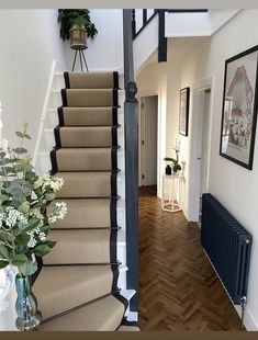 there is a vase with flowers sitting on the stair case next to the stairs in this house