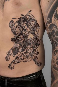 a man with tattoos on his stomach has a tiger and demon tattoo on his chest