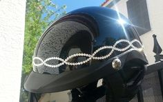 a motorcycle helmet with pearls on it is parked in front of a white building and trees