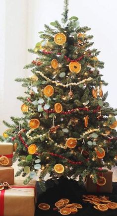 a small christmas tree is decorated with oranges and gold ornaments, along with presents