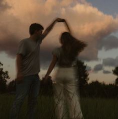 two people standing in the grass with their arms around each other as they hold hands