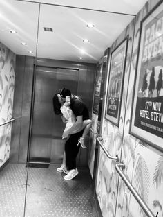 a man and woman are kissing in an elevator with posters on the wall behind them