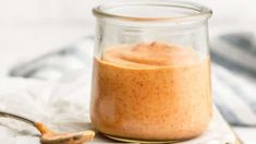 a glass jar filled with food sitting on top of a table next to a spoon