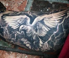 a man's arm with an eagle tattoo on it, in front of a brick wall